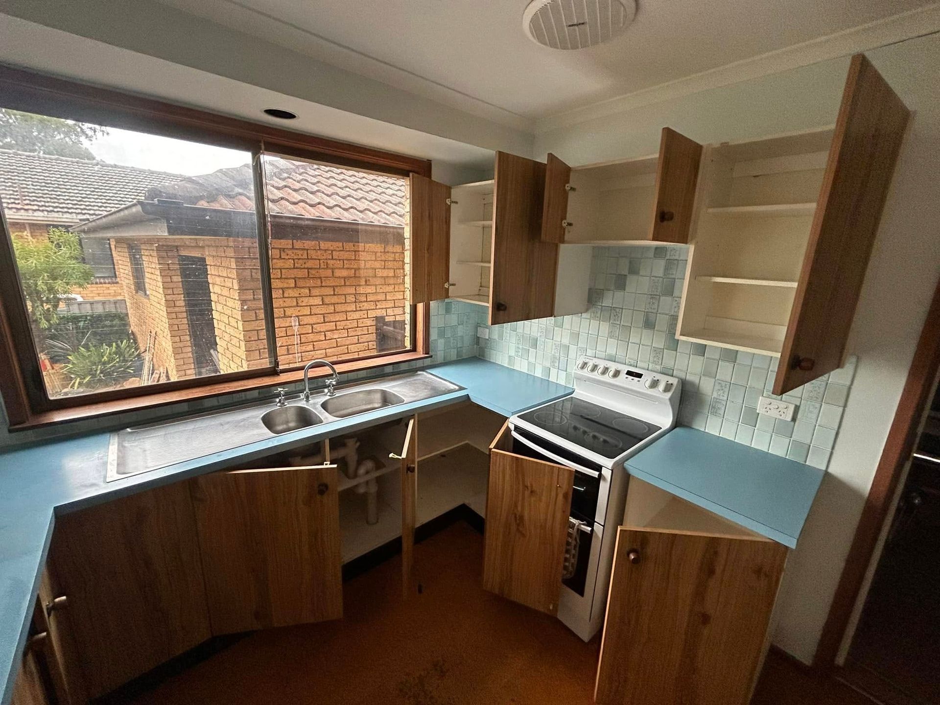 An empty kitchen with wooden cabinets and a stove
