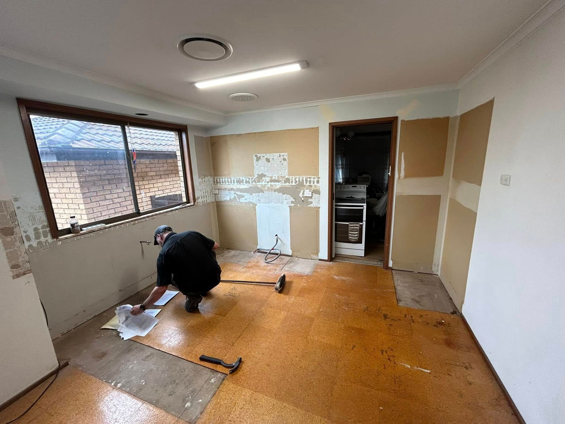 A man is working on a wooden floor in a room.