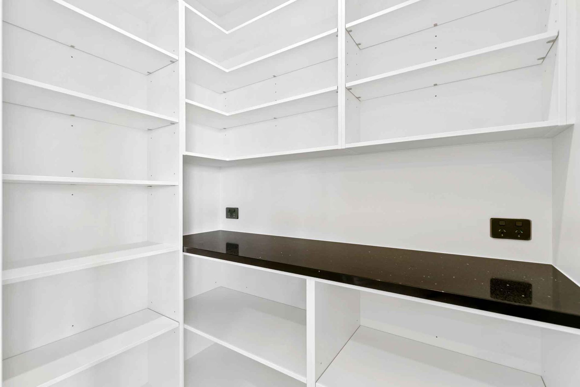 A room with lots of shelves and a black counter top.