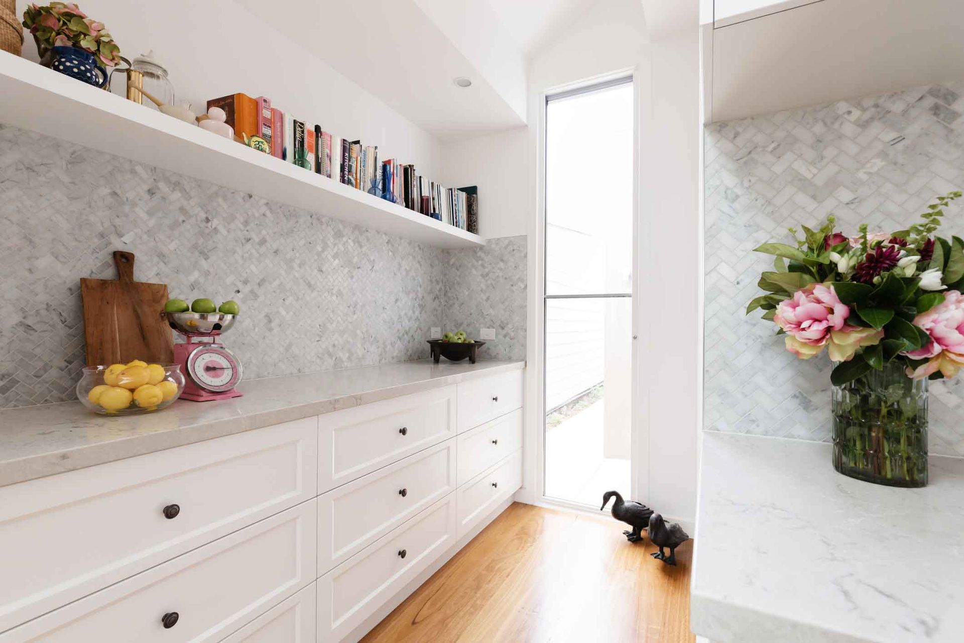 A kitchen with white cabinets and a vase of flowers on the counter.