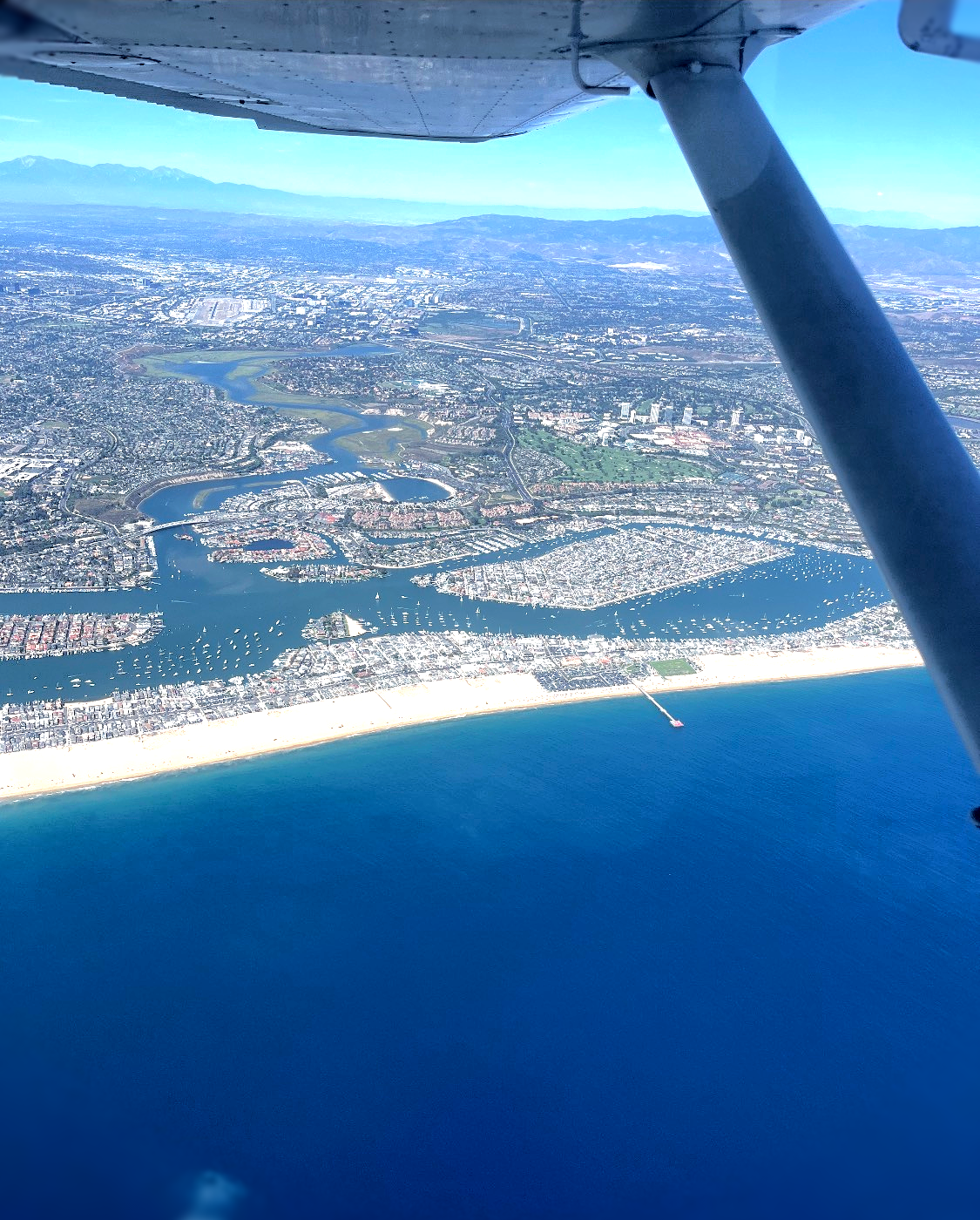 A man wearing headphones is flying a plane over a body of water