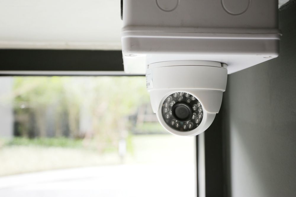 White Security Camera Mounted on A Wall Near a Window — CQR Locksmiths in Walgett, NSW