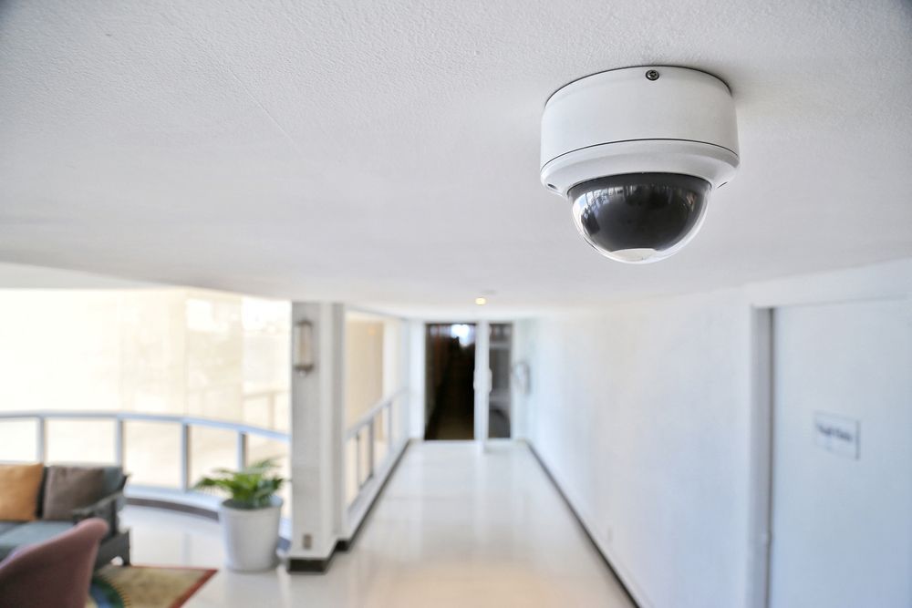 Security Camera on Ceiling in Hallway Overlooking a Seating Area and Doorways — CQR Locksmiths in Narrabri, NSW