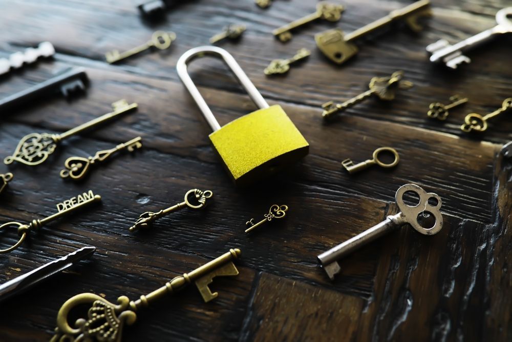 Yellow Padlock Surrounded by Various Antique Keys on A Dark Wood Surface — CQR Locksmiths in Wee Waa, NSW