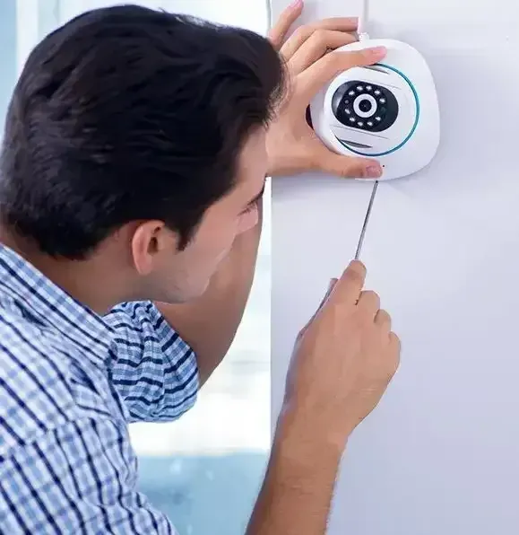 Man Using A Screwdriver To Install A White Security Camera On A White Wall — CQR Locksmiths In Moree, NSW