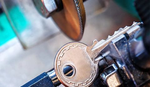 Key Being Shaped On A Key-Cutting Machine With A Grinding Wheel In Close-Up View — CQR Locksmiths In Moree, NSW