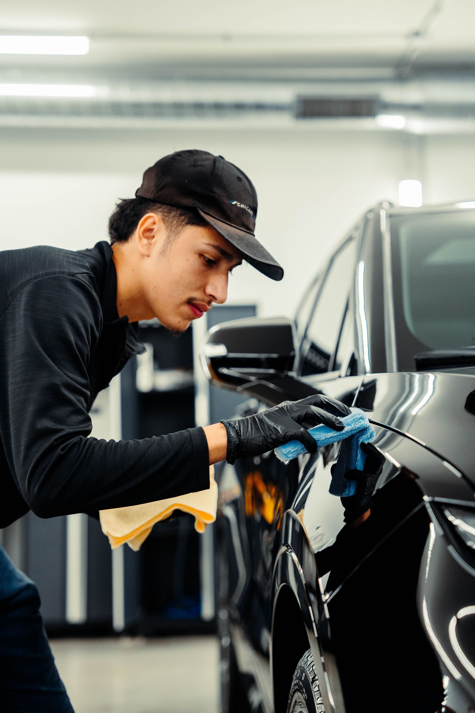 A man is cleaning a car with a cloth in a garage.