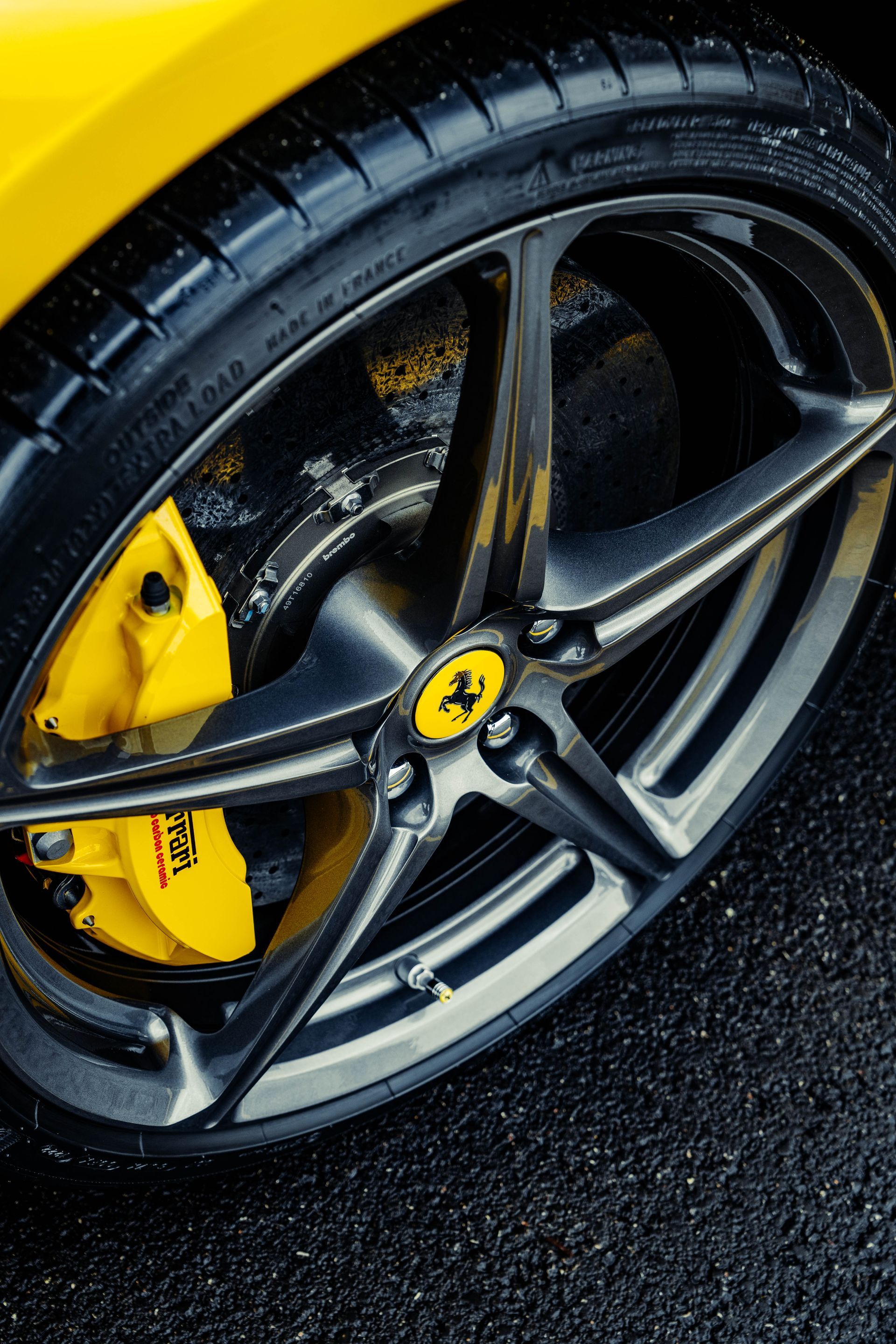 A close up of a yellow ferrari wheel with yellow brake calipers.