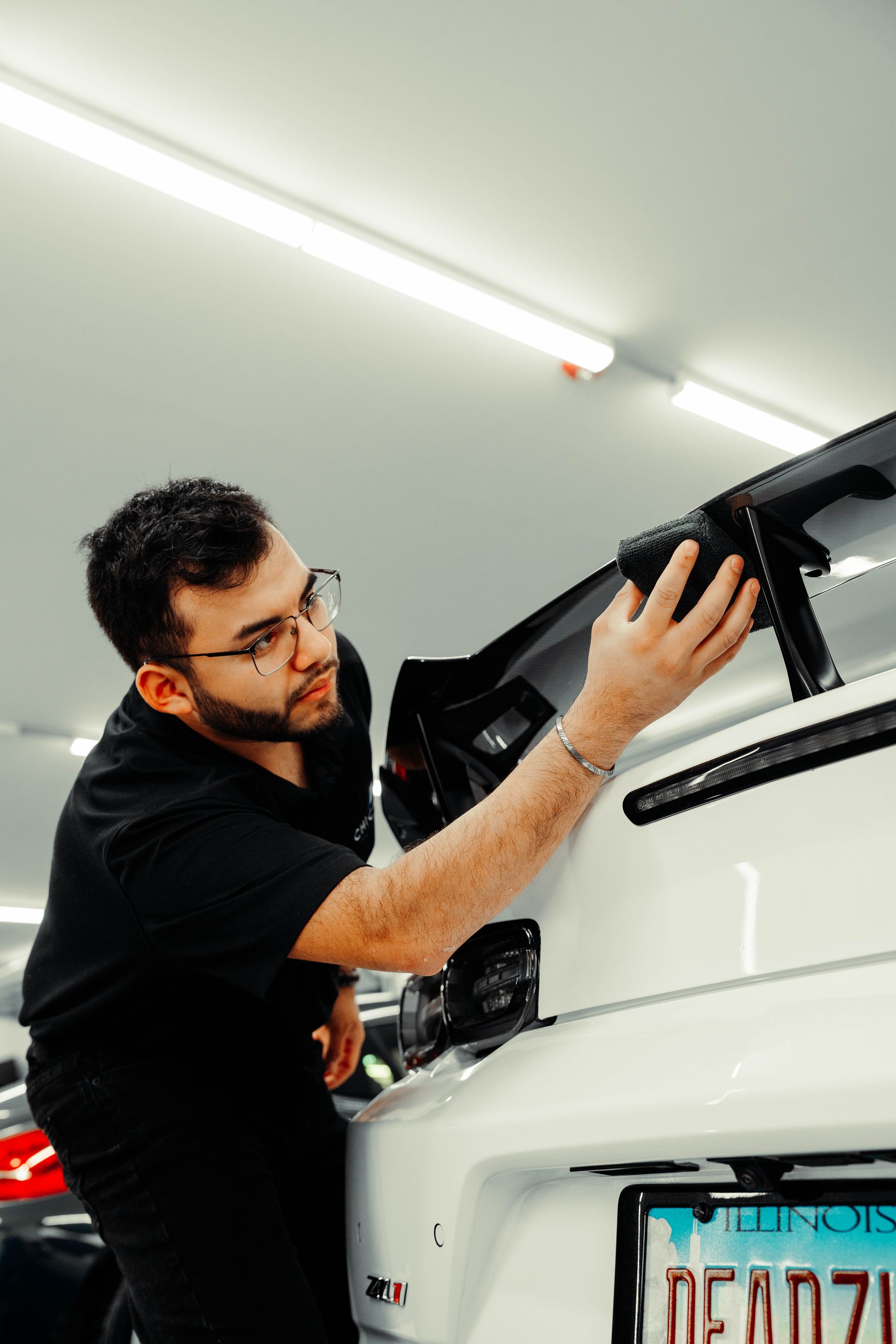 A man in a black shirt is working on a white car.