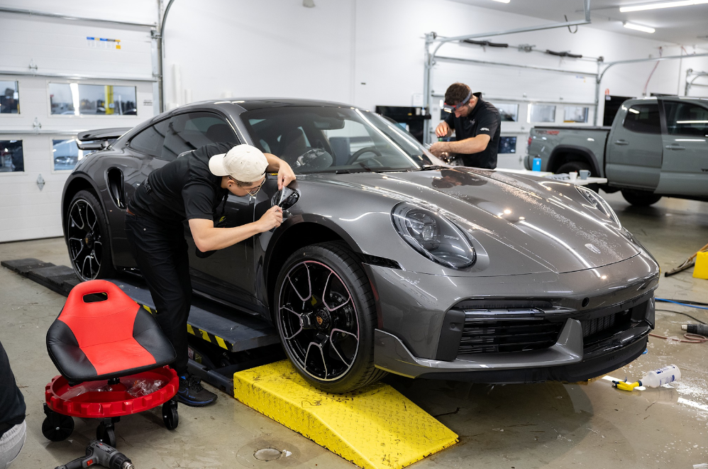 a black porsche is parked in a parking lot with its door open
