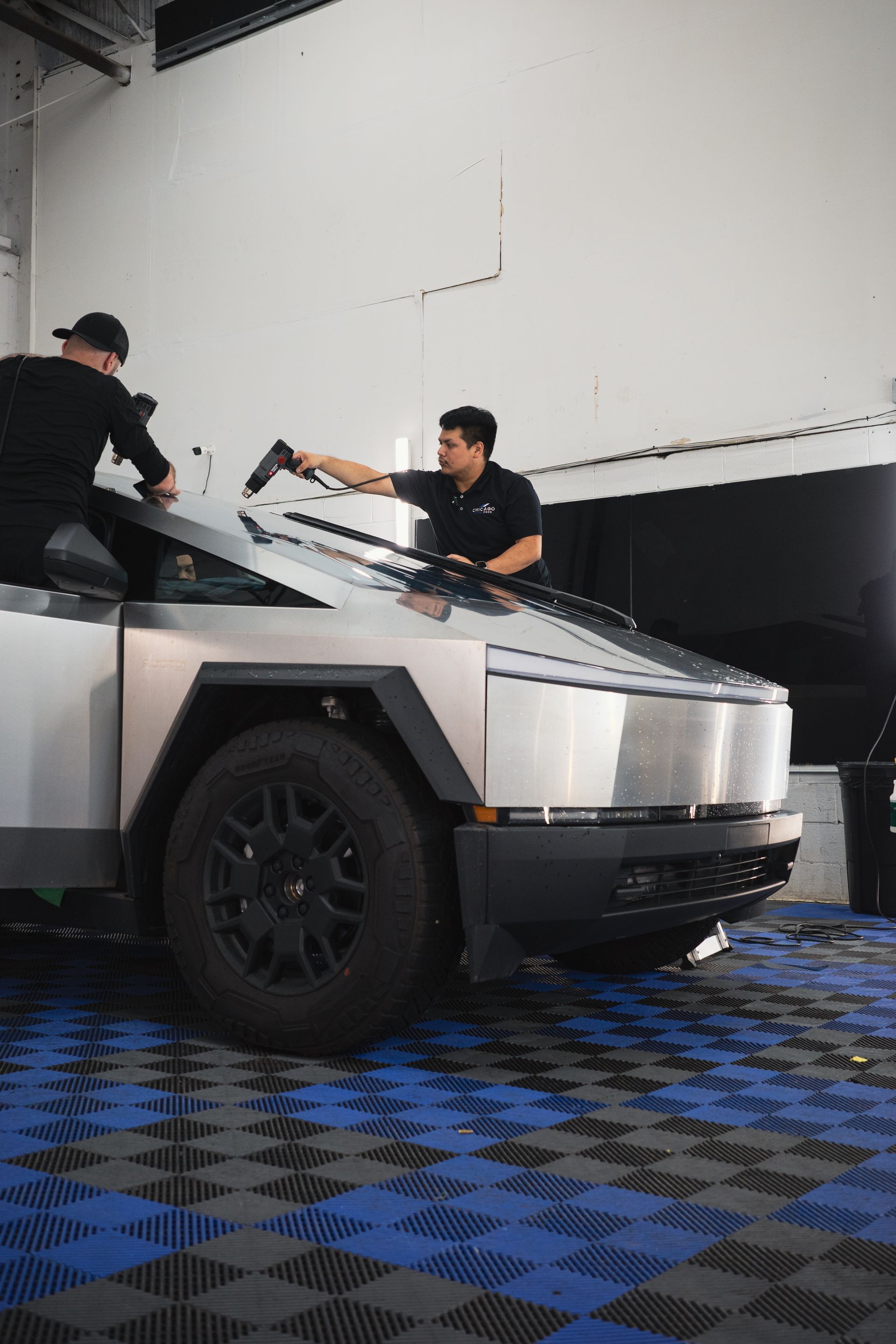 Two men are working on a tesla cybertruck in a garage.