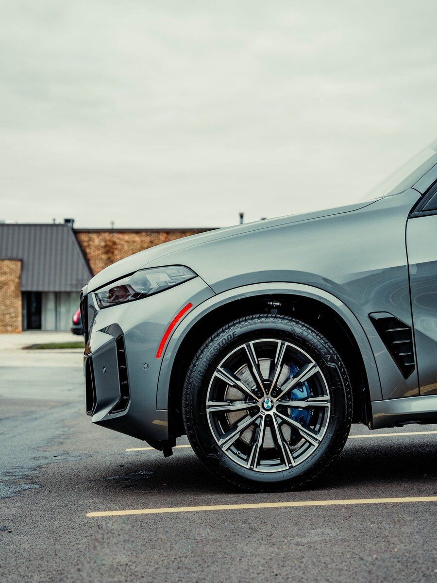 A silver bmw x5 is parked in a parking lot.