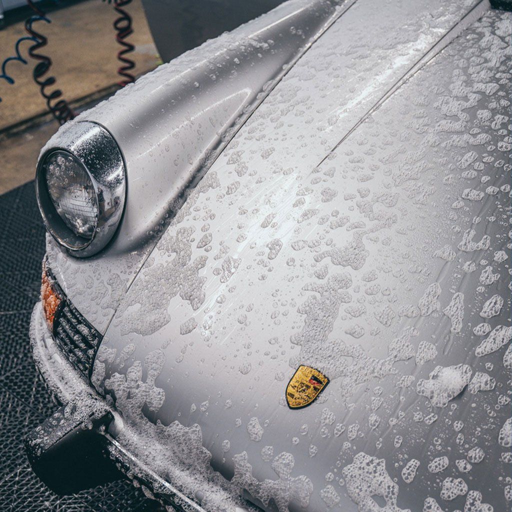 A silver porsche is covered in foam and bubbles