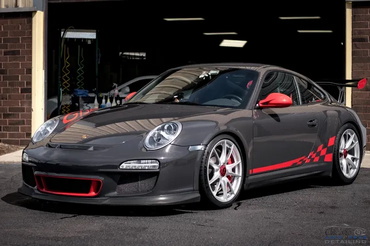 A gray porsche 911 gt3 rs is parked in front of a brick building.