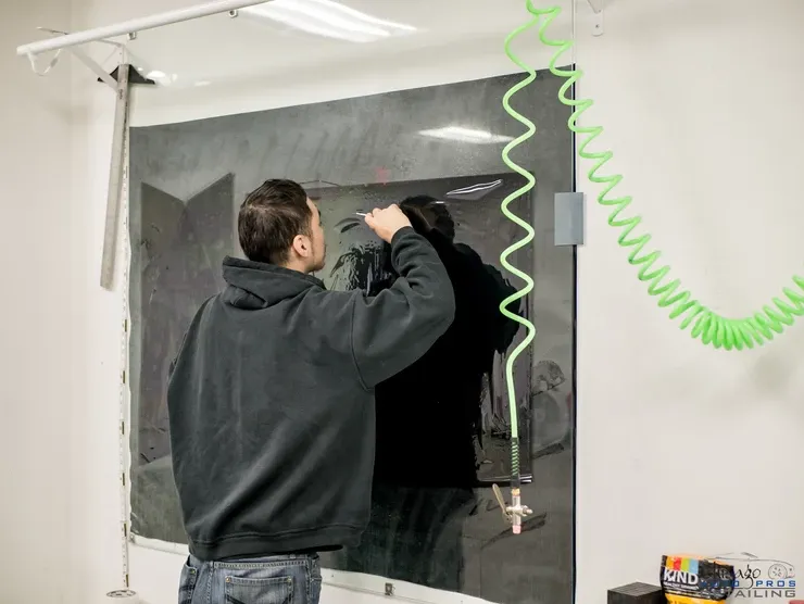 A man is working on a window with a green hose hanging from the ceiling