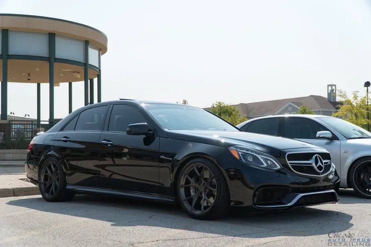Two black mercedes benz cars are parked next to each other in a parking lot.
