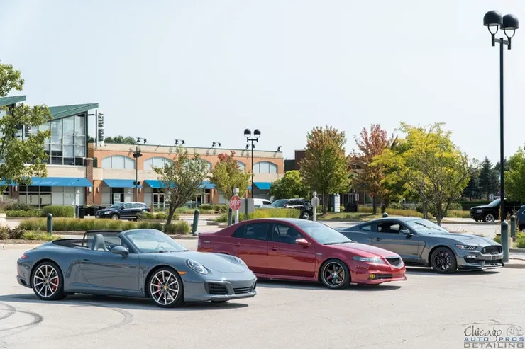 Three cars are parked in a parking lot in front of a building.