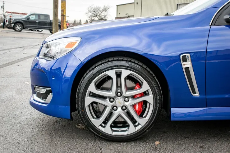 A blue car with red brake calipers is parked on the side of the road.