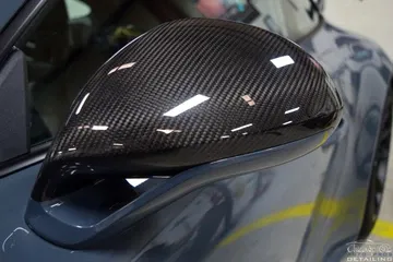 A close up of a carbon fiber rear view mirror on a car