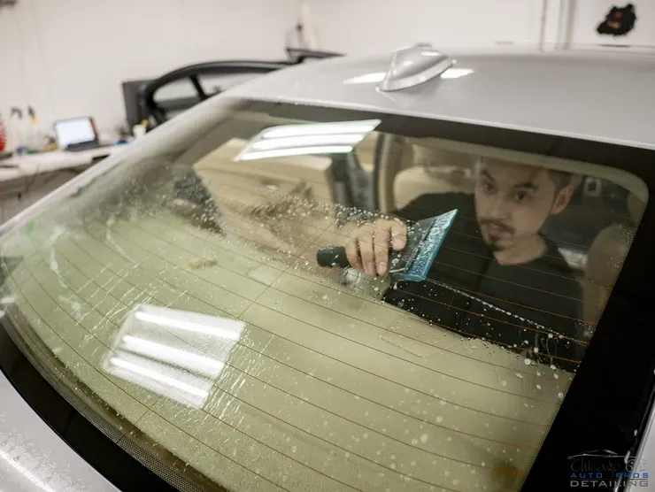 A man is cleaning the windshield of a car.
