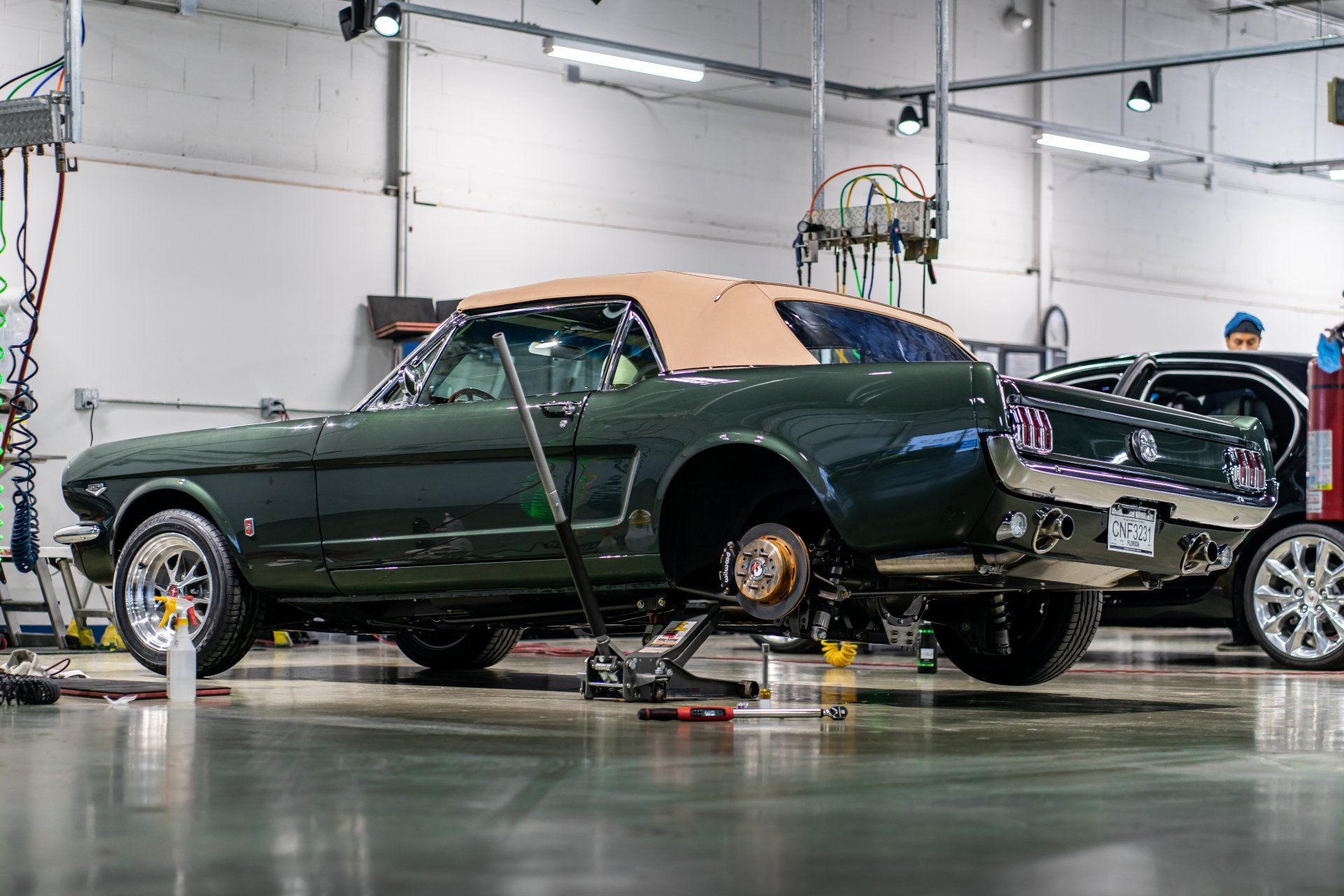 A green mustang is being worked on in a garage.