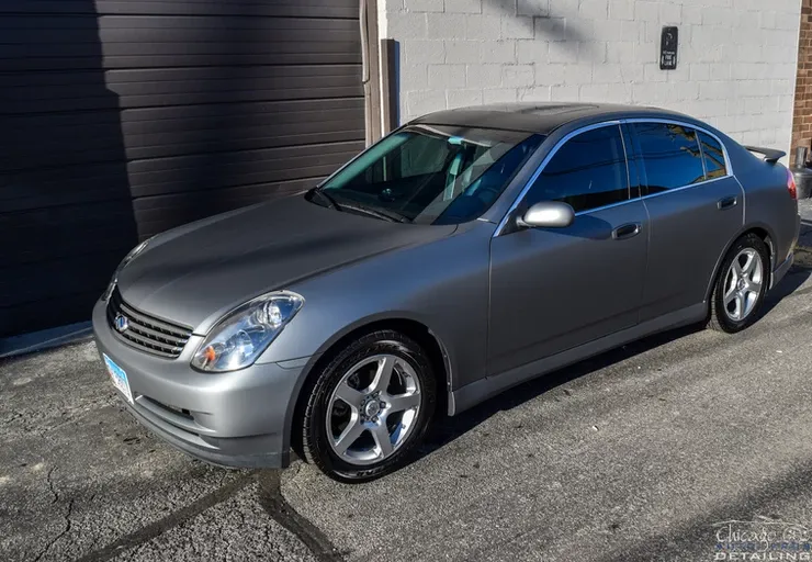 A silver car is parked in front of a garage.