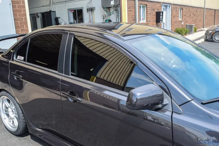 A black car is parked in front of a brick building
