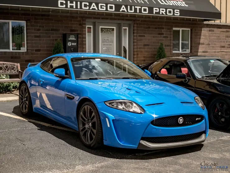A blue sports car is parked in front of a chicago auto pros building.