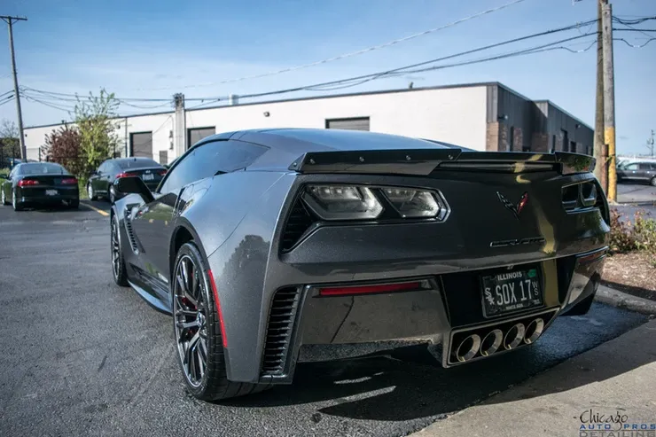 A gray sports car is parked in a parking lot in front of a building.