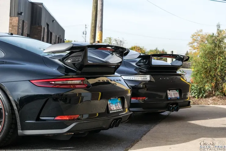 Three black porsche 911 gt3 rs are parked next to each other in a parking lot.
