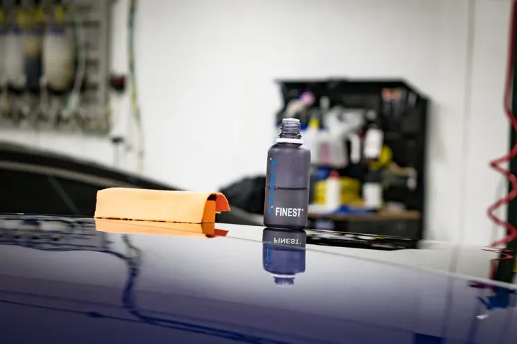 A bottle of ceramic coating is sitting on the roof of a car.