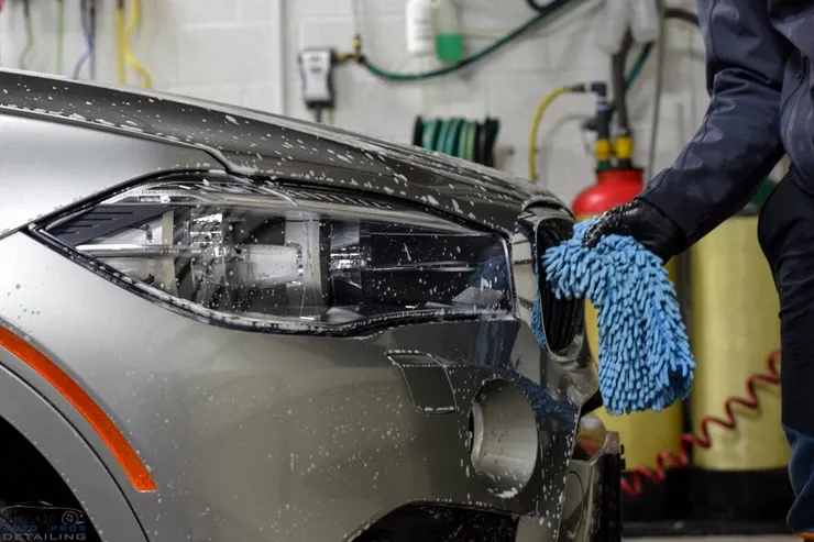 A person is washing a car with a blue towel.