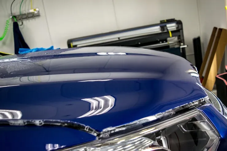 A close up of the hood of a blue car in a garage.