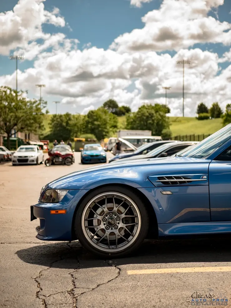 A blue car is parked in a parking lot with other cars.