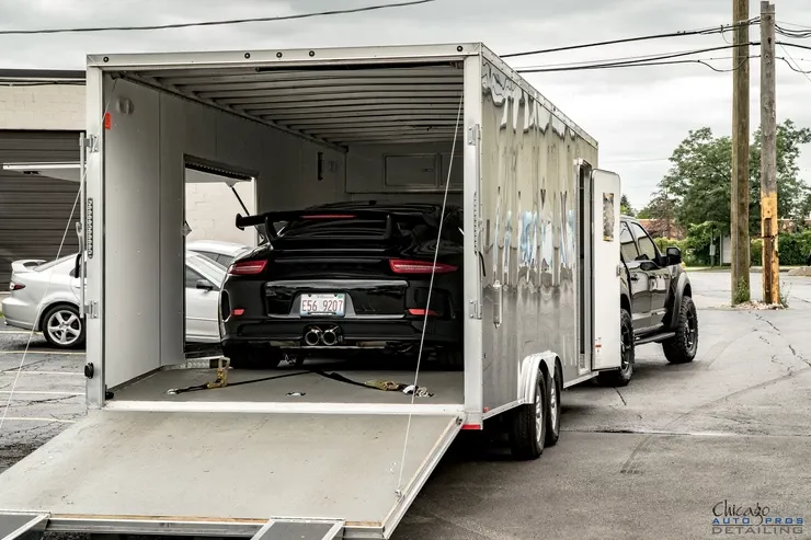 A car is being towed by a trailer in a parking lot.