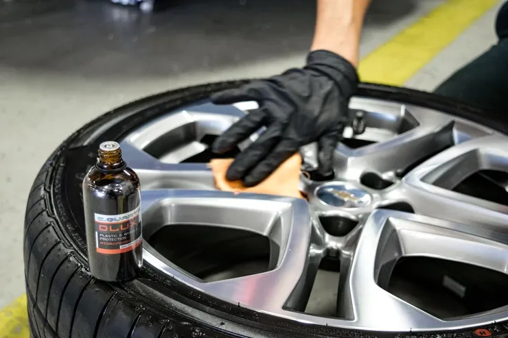 A person is cleaning a car wheel with a sponge.