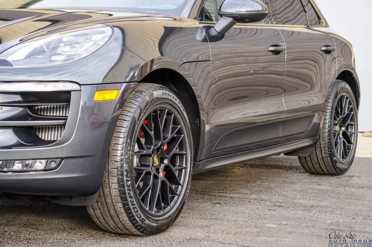 A black porsche macan turbo is parked in a parking lot.