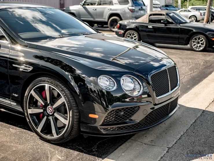 A black bentley is parked on the side of the road.