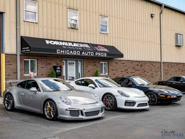 A row of porsche cars are parked in front of a building.
