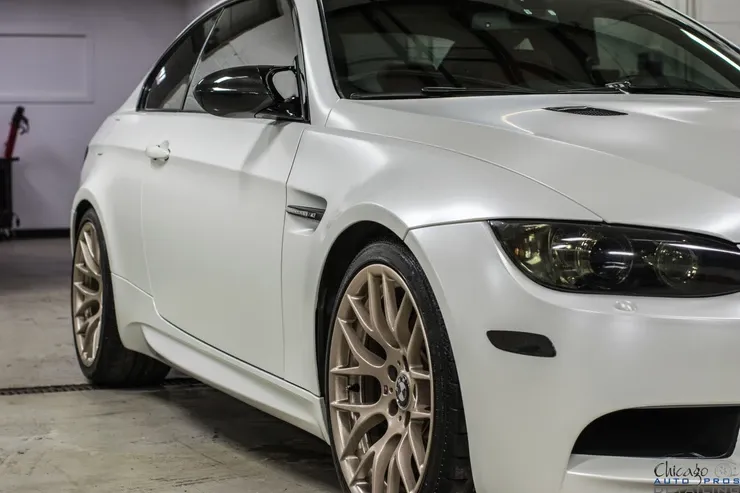 A white bmw m3 is parked in a garage.