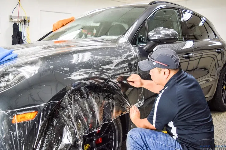 A man is wrapping a car with plastic wrap in a garage.
