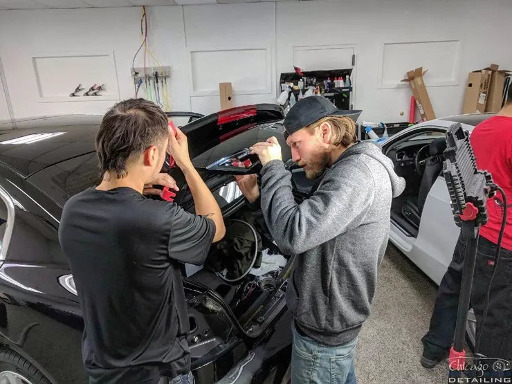 Two men are working on a car in a garage.