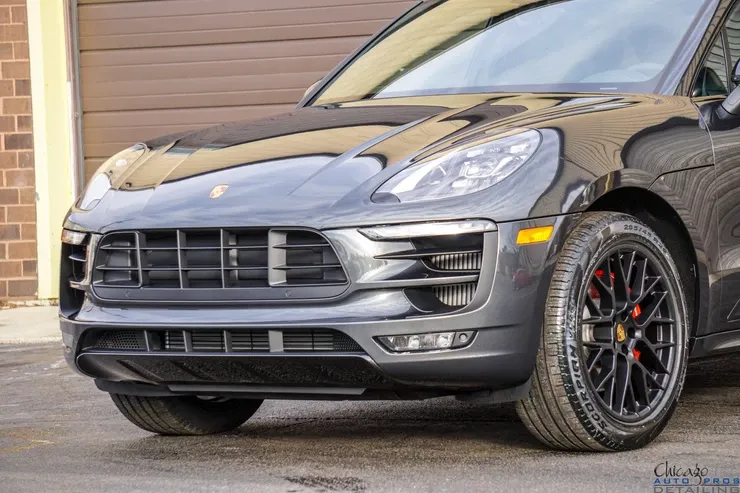 A black porsche macan turbo is parked in front of a garage door.