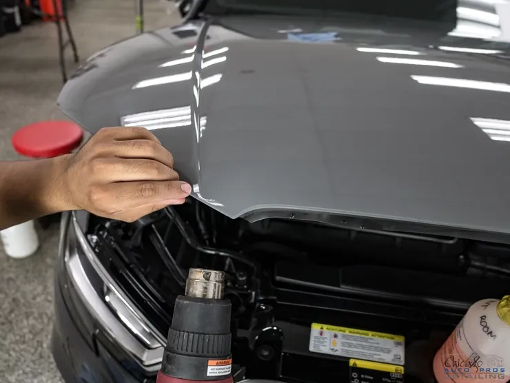 A person is applying a hood protector to a car.