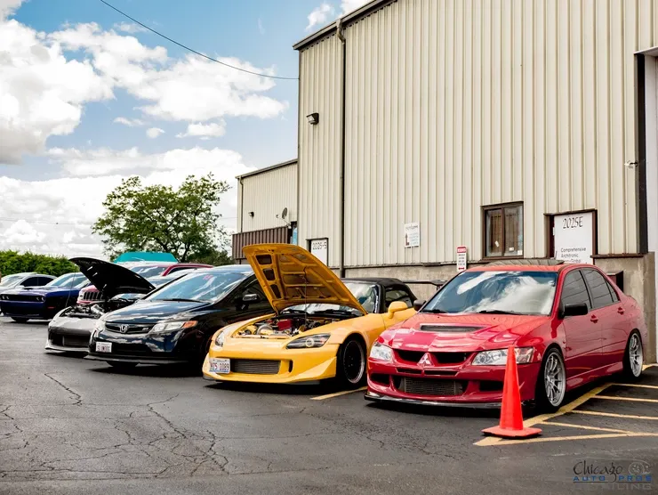 A row of cars parked in front of a building with the hoods up.