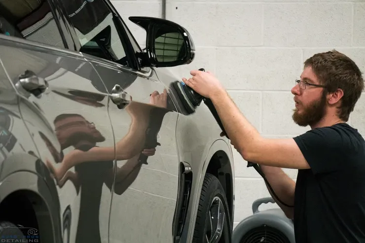 A man is polishing a car with a polisher.