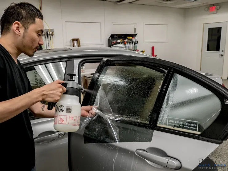 A man is spraying a car with a spray bottle.