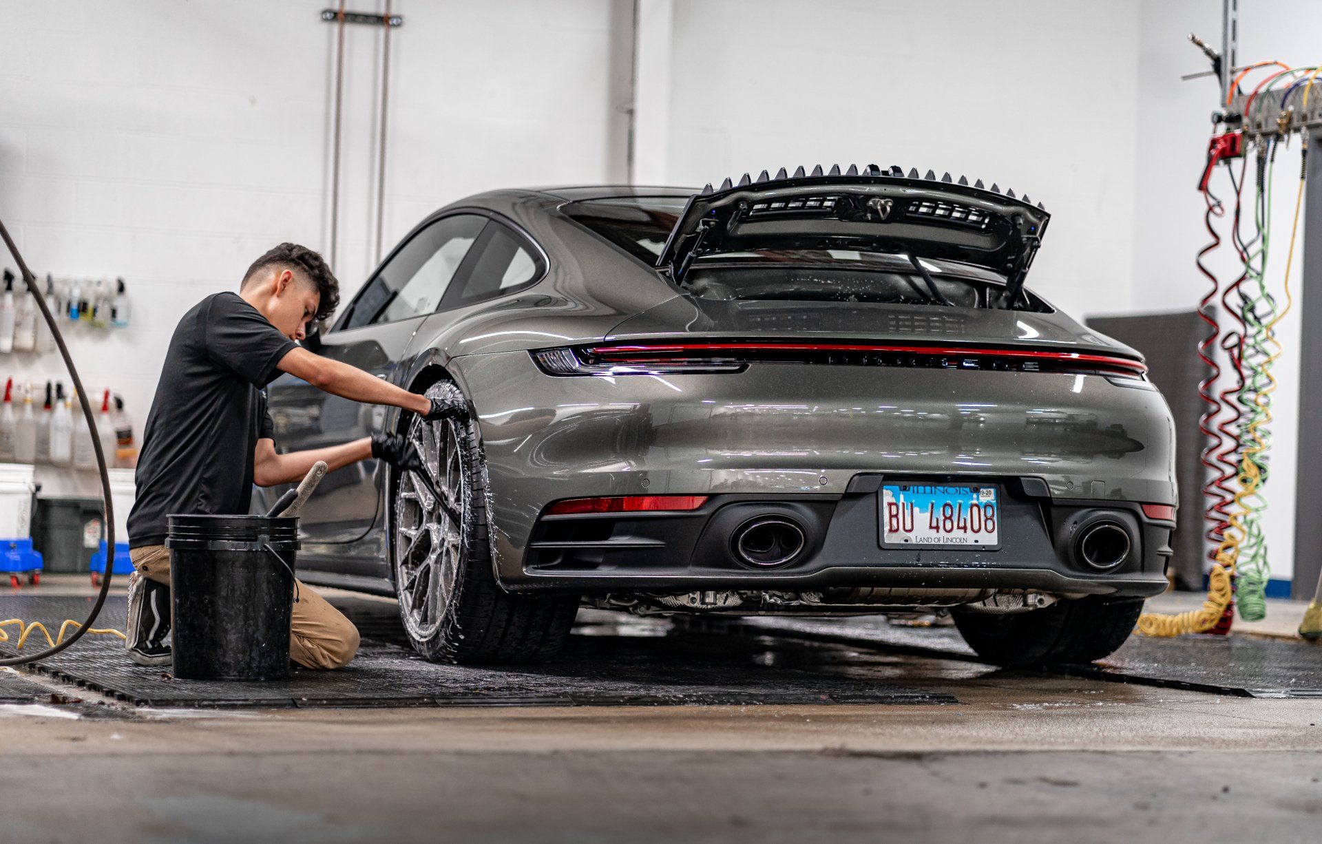 A man is washing a porsche 911 in a garage.