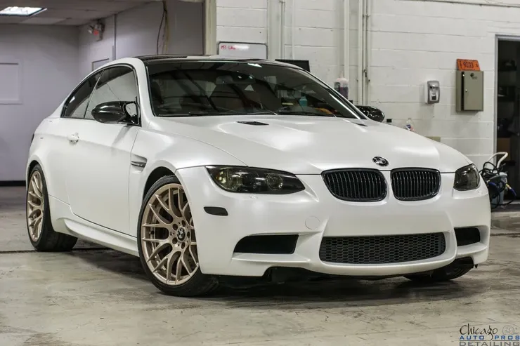 A white bmw m3 is parked in a garage.