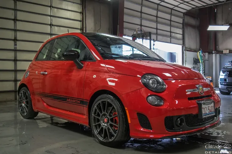 A red fiat 500 is parked in a garage.